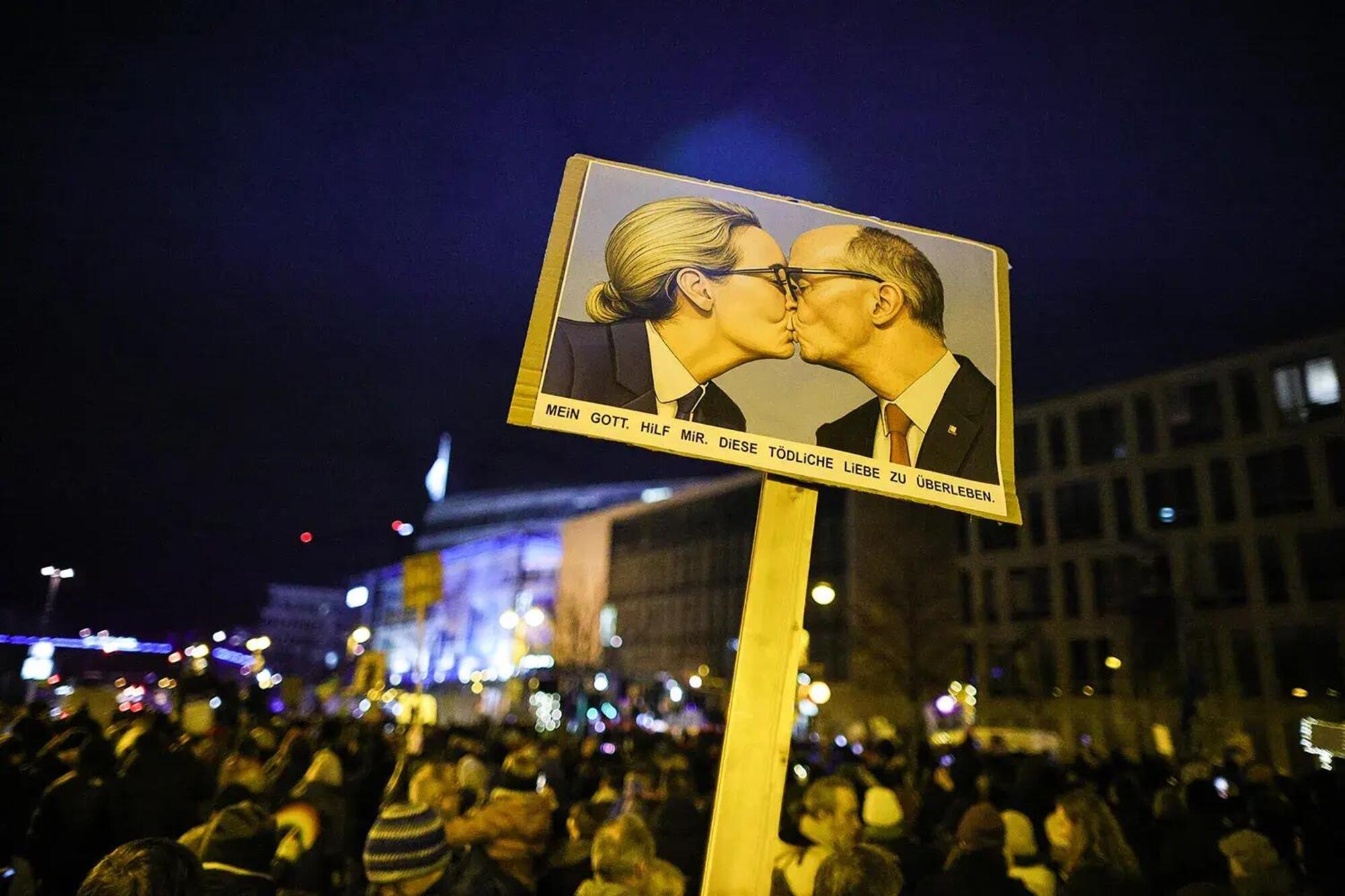 Un cartellone generato con Ia durante una protesta in cui Alice Weidel (Afd) e Friedrich Merz (Cdu) si baciano 